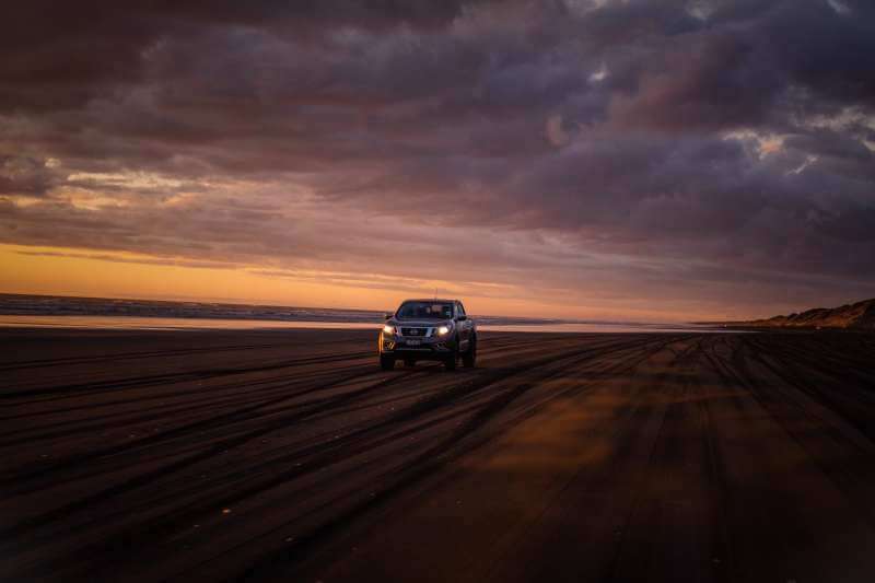 有夕陽的海邊沙灘上，緩慢開著休旅車享受悠閒時刻